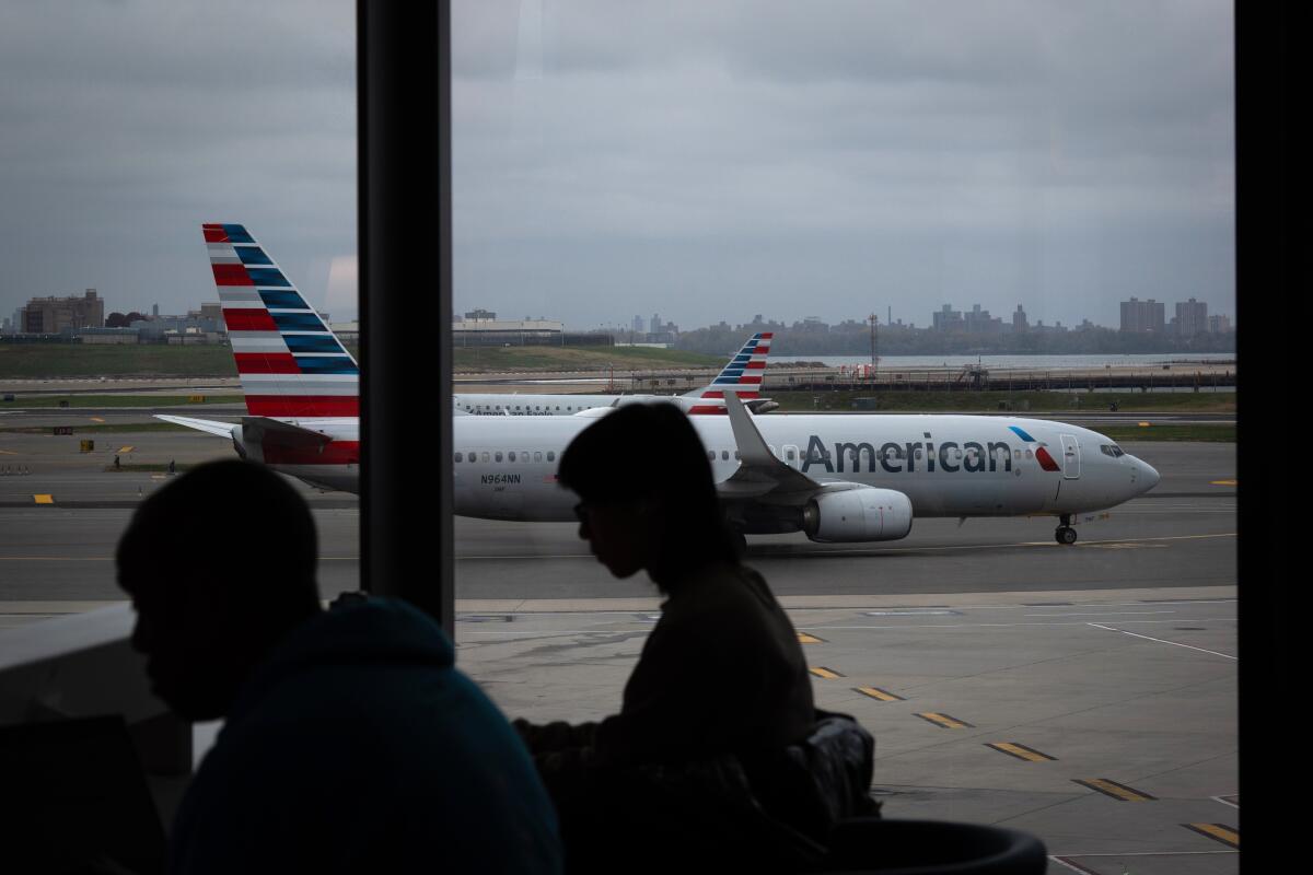 Gente esperando a vuelos mientras un avión de American Airlines circula por la pista en el aeropuerto de Portland (PDX), el martes 11 de noviembre de 2025.